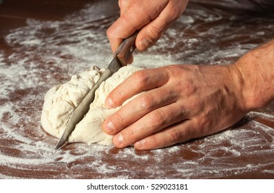 Male hand cut the dough for baking .