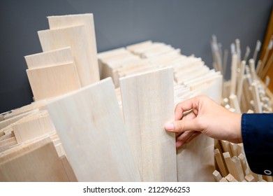 Male Hand Designer Choosing Beige Balsa Wood Plank In Stationery Shop. Wooden Material For Making Art And Craft Model. Wood Industry Concept