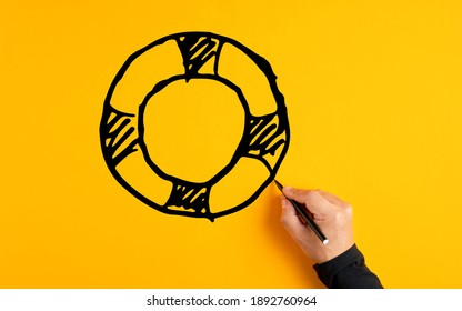 Male Hand Drawing A Lifesaver Or Lifebuoy Sketch On Yellow Background. Insurance, Safety, Assistance Or Aid In Business Concept.