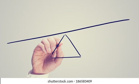 Male hand drawing a seesaw showing an imbalance with one end lower than the other. - Shutterstock ID 186583409