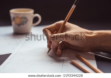 male hand drawing storyboard conceptual ideas with coffee cup in the background, hard work sketching art concept