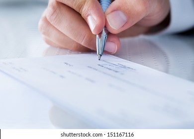 A Male Hand Filling Out The Amount On A Cheque