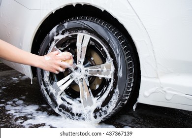 male hand with foam sponge washing car wheel