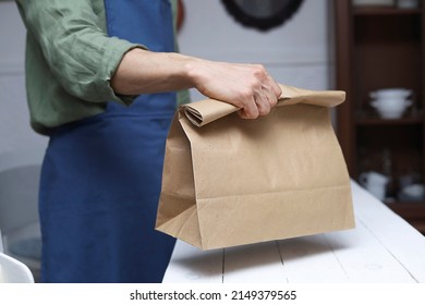 Male hand giving blank paper bag in a zero waste shop. Shop assistant serving customers. Mock-up.Space for logo or design. - Powered by Shutterstock