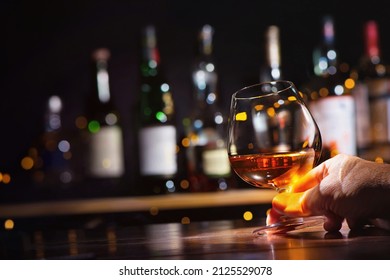 Male hand with glass of whiskey or brandy on bar counter