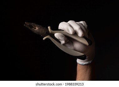 Male Hand In Glove Close Up Holding Side-cutting Lineman Pliers Over Black Background.