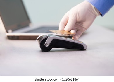 Male Hand In A Glove Holding A Contactless Card Over A Card Reader