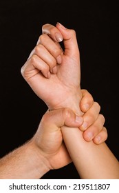 Male Hand Grabbing Female Wrist On Black Background