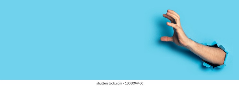 Male hand grabs something on a blue background. Banner