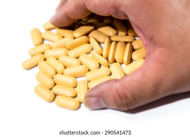 Male Hand Grabs Yellow Multi-vitamin B Focused On The Pills Isolated On White   Background 
Drug Pill.Vitamin Pills,grab Vitamin. Vitamin C.Vitamin C Pills.Take Vitamin C.Taking Vitamin C.Vitamin C