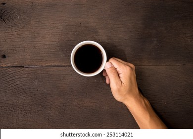 Male Hand Hold Mug Of Espresso Coffee On Wood Table.