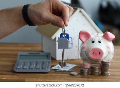 Male Hand Hold Silver Key. Calculator With Piggy Bank Against Home Background Closeup. Mortage Credit Concept