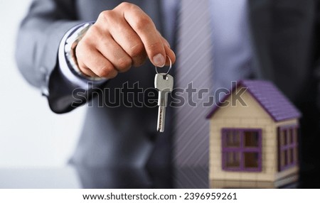 Male hand hold silver key giving it to buyer or take it closeup. New owner pledge idea for life, family solution man arm credit negotiation clerk in office future plan concept