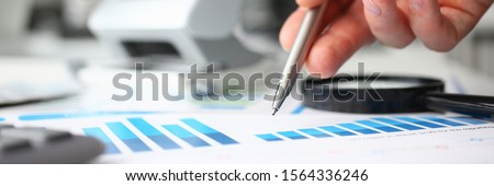 Male hand hold siver ball pen infographics at office table closeup. Internal Revenue Service inspector sum check, investigation, exchange market, earnings, savings, loan and credit concept