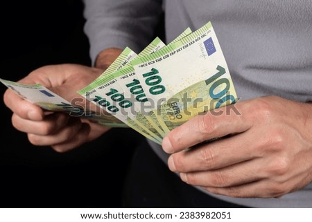 Male hand holding 100 euro bills close up.