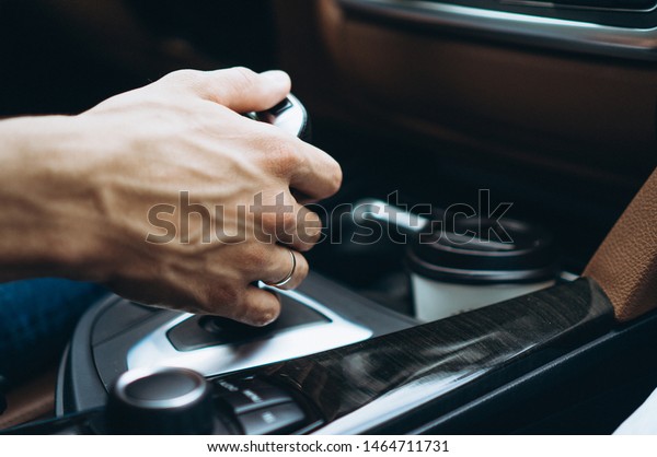 Male\
hand holding automatic transmission in car close\
up