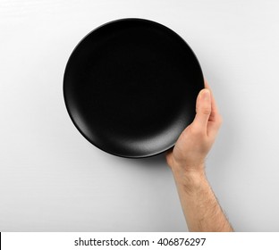 Male Hand Holding Black Plate, Isolated On White