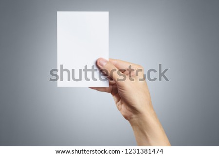 Male hand holding a blank card 10x15cm on grey background