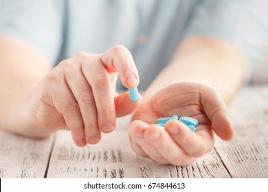 Male hand holding blue pills in palm