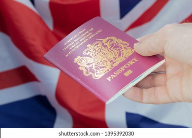 Male Hand Holding a British Passport Against a Union Jack Backdrop