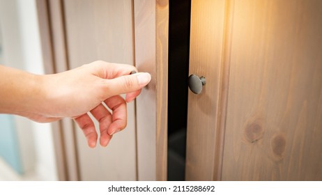 Male Hand Holding Cabinet Door Knob Opening Wooden Cupboard. Home Decoration Concept