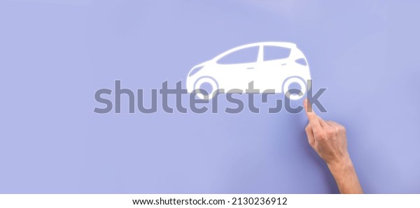 Male hand holding car auto icon on grey\
background. Wide banner composition.Car automobile insurance and\
collision damage waiver\
concepts.
