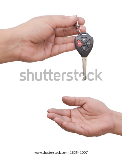 Male hand holding a car key and handing it over\
to another person. isolated\
