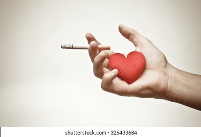 male hand holding a cigarette with a red heart / making to right decision about smoking concept