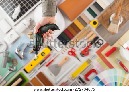 Male hand holding a drill, build and renovation tools on background top view, DIY and improvement concept