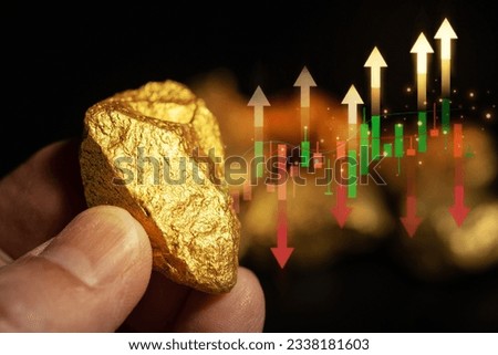 Male hand holding gold ingot and fluctuating gold price chart with rising and falling prices on black background.