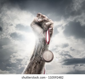 Male hand holding gold medal against the dramatic sky - Powered by Shutterstock