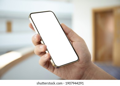 male hand holding golden phone with isolated screen in hotel lobby 