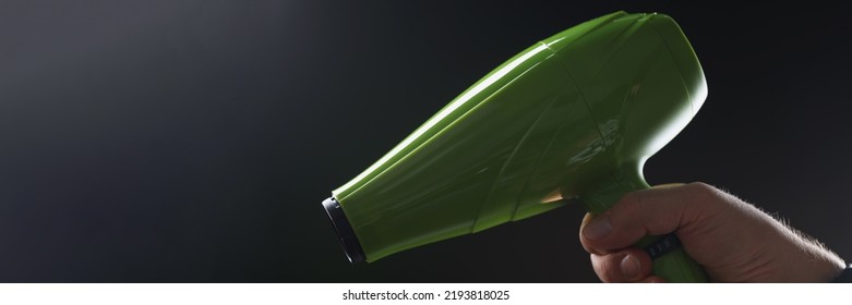 Male Hand Holding Green Hair Dryer On Black Background Closeup