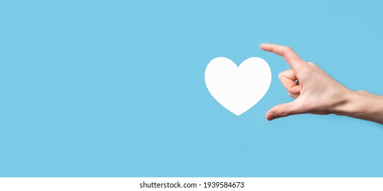 Male Hand Holding Heart , Like Icon On Blue Background. Kindness, Charity, Pure Love And Compassion Concept.Banner With Copy Space.