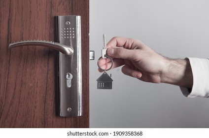 Male hand holding house key at home.
