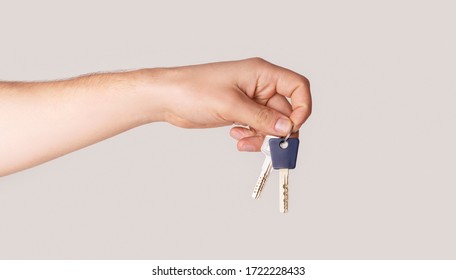 Male Hand Holding House Keys On Light Background, Close Up. Panorama