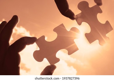 männliche Hand hält Puzzle mit Sonnenlicht Effekt Himmelswolken. Strategien für den Geschäftserfolg. Konzept der Zusammenarbeit und Teamarbeit. 