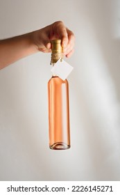 Male Hand Holding Little Glass Bottle Of Pink Rosa Wine Or Liquor With No Brand Label, Mock Up. Vertical Shot, White Background, Copy Space