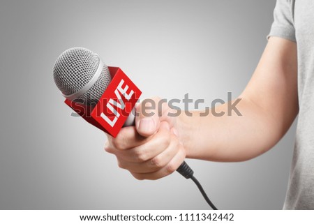 Male hand holding a microphone, isolated on grey background