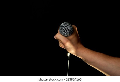 Male Hand Holding Microphone With Wire Cable Isolated On Black Background