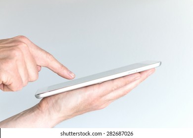 Male Hand Holding Modern Tablet Or Large Smart Phone. Other Hand Pointing At Screen Of Mobile Device With One Finger. Concept Of Mobile Computing And Information Technology.