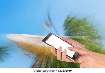 Male Hand Is Holding A Modern Touch Screen Phone And Image Of Large Sattelite Dish  And Blue Sky In Background.