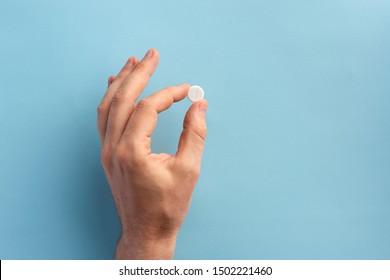 Male hand holding one pill. Flat lay.