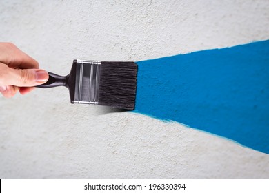 Male Hand Holding Paint Brush And Painting White Wall With Blue Color.