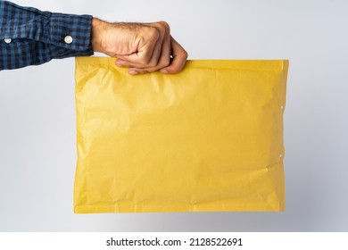 Male Hand Holding Parcel Post Against White Background, Close Up