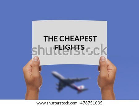 Male hand holding a piece of paper. The cheapest flights written. Blue sky with blurry plane in the background