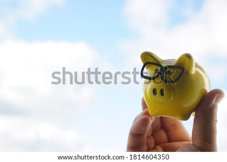 male hand holding Piggy bank with coins on blue sky  background.