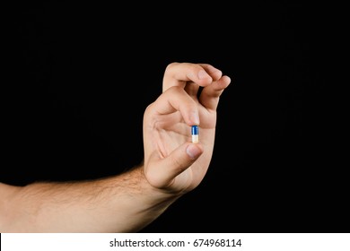 Male Hand Holding Pill Isolated On Black Background. The Concept Of Medicine And Health