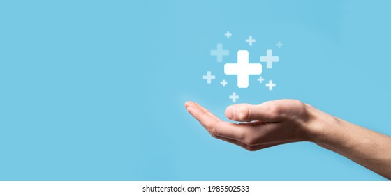 Male hand holding plus icon on blue background. Plus sign virtual means to offer positive thing like benefits, personal development, social network Profit,health insurance, growth concepts.