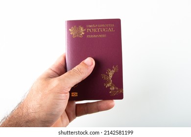 Male hand holding portuguese passport over white background.